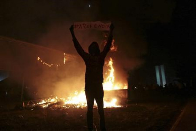 a demonstrator holds a sign next to street structures set on fire during a protest against the confederations cup and president dilma rousseff 039 s government in front of the national congress in brasilia photo reuters ueslei marcelino