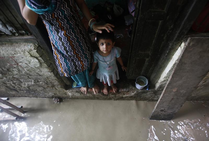 a child watches while standing on the doorstep of her house next to a flooded alley photo reuters