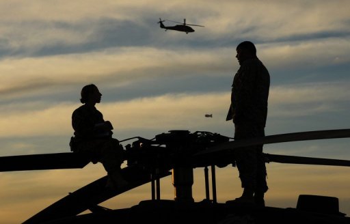 two us army helicopter pilots talk on top of their blackhawk helicopter at kandahar airbase photo afp