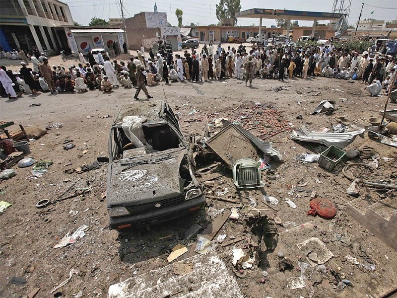 crowd gathers near the wreckage of a car used in a bomb attack on a convoy of paramilitary frontier corps in peshawar photo afp