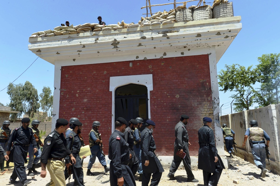 security officials walk past a bullet riddled security checkpoint following an overnight attack by armed militants at jina kor 40 kilometres southeast of peshawar on july 3 2013 photo afp