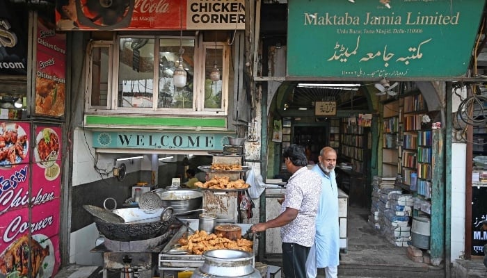 a shop owner right standing outside his urdu literature bookshop at urdu bazar in the old quarters of delhi on october 14 2024 photo afp