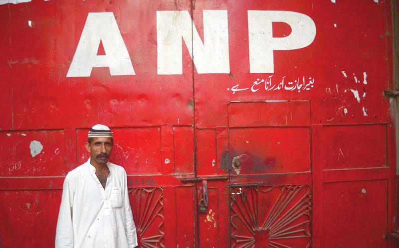 a supporter of the awami national party stands outside the closed doors of the party s office in sohrab goth karachi the party decided to keep their offices shut following a string of attacks on its offices during the elections photo file