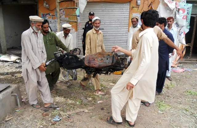 pakistani residents move the wreckage of a motorcycle after a bomb explosion photo afp pakistani residents move the wreckage of a motorcycle after a bomb explosion photo afp