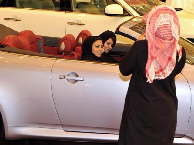 a saudi man takes a picture of two women sitting in a car at an auto show in jeddah photo afp