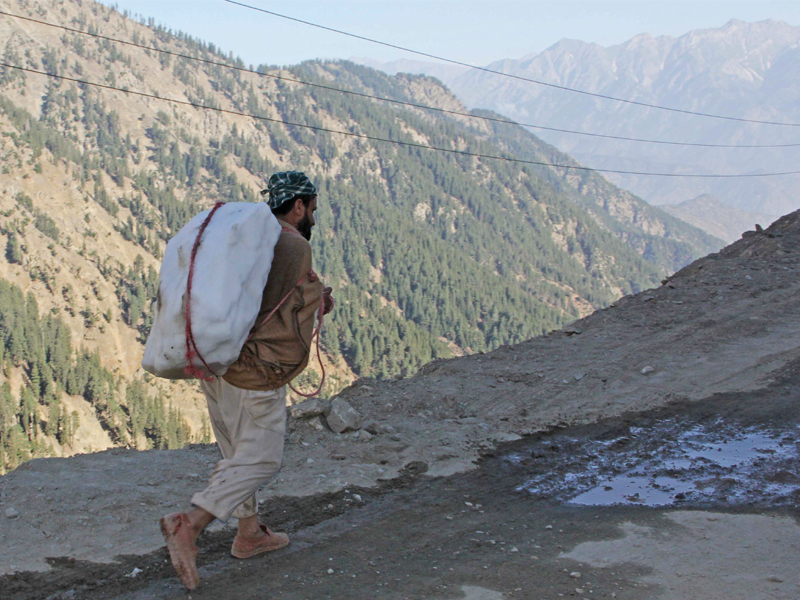 a man carries a slab of ice to be sold to dealers photo fazal khaliq express