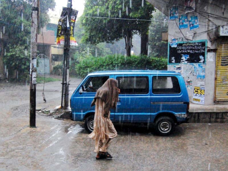 a man covers his head while walking amid heavy rain in islamabad photo muhammad javaid express