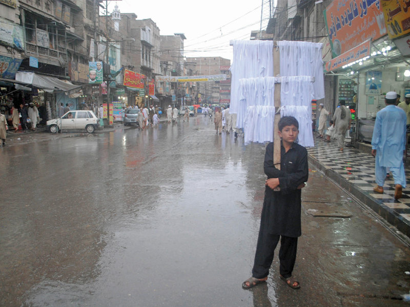 a child sells his wares in qissa khwani bazaar during the rain heavy rain spells have caused water levels in major k p rivers to rise which may trigger floods in central districts photo muhammad iqbal express