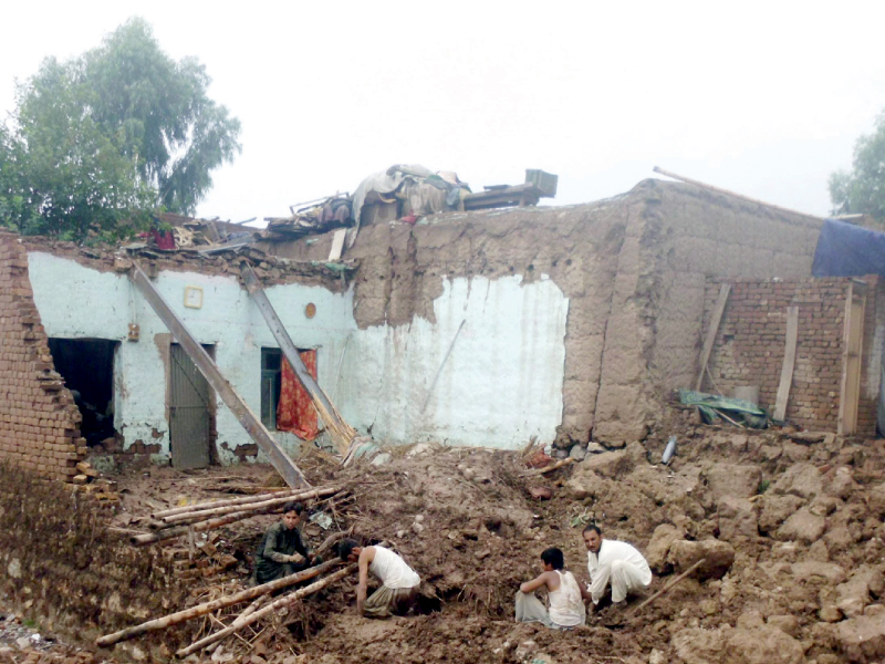 residents sit on the debris of a demolished house after torrential rains wreaked havoc in the jamrud district photo express