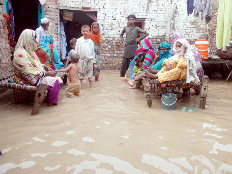 residents of micro colony in sukkur sit on charpoys after rainwater entered their homes on saturday photo express naeem ahmed ghouri