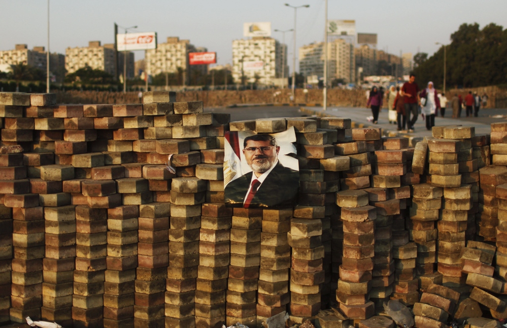 supporters of deposed egyptian president mohamed mursi depicted in poster walk behind a makeshift barrier built to demarcate their sit in area around raba 039 al adawya mosque east of cairo august 3 2013 photo reuters