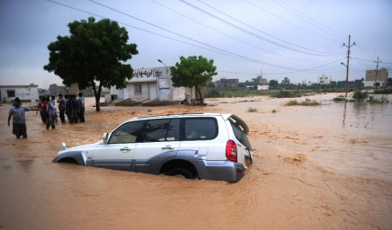 residents stand near a partially submerged vehicle as they evacuate a flooded area in karachi on august 4 2013 photo afp