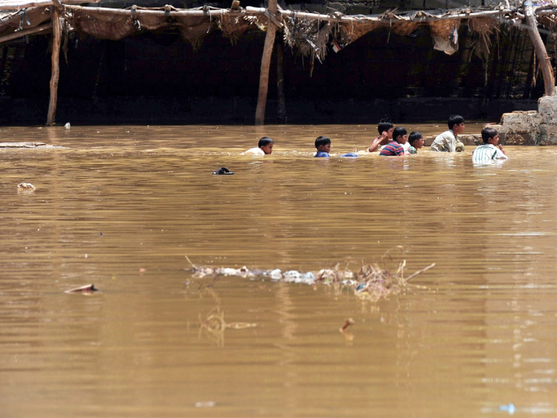 youth swim in floodwaters on monday following heavy monsoon rains in karachi photo afp