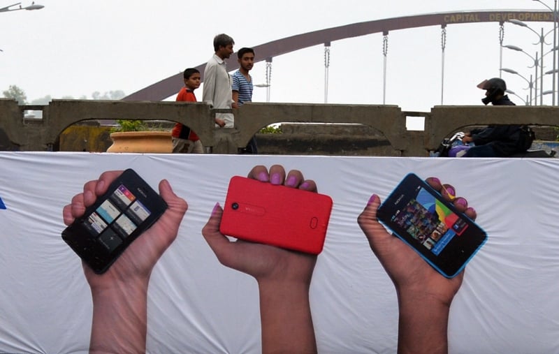 pedestrians walk past a mobile phones promotion banner in islamabad on august 6 2013 photo afp