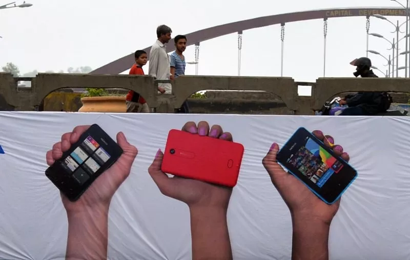 pedestrians walk past a mobile phones promotion banner in islamabad on august 6 2013 photo afp pedestrians walk past a mobile phones promotion banner in islamabad on august 6 2013 photo afp