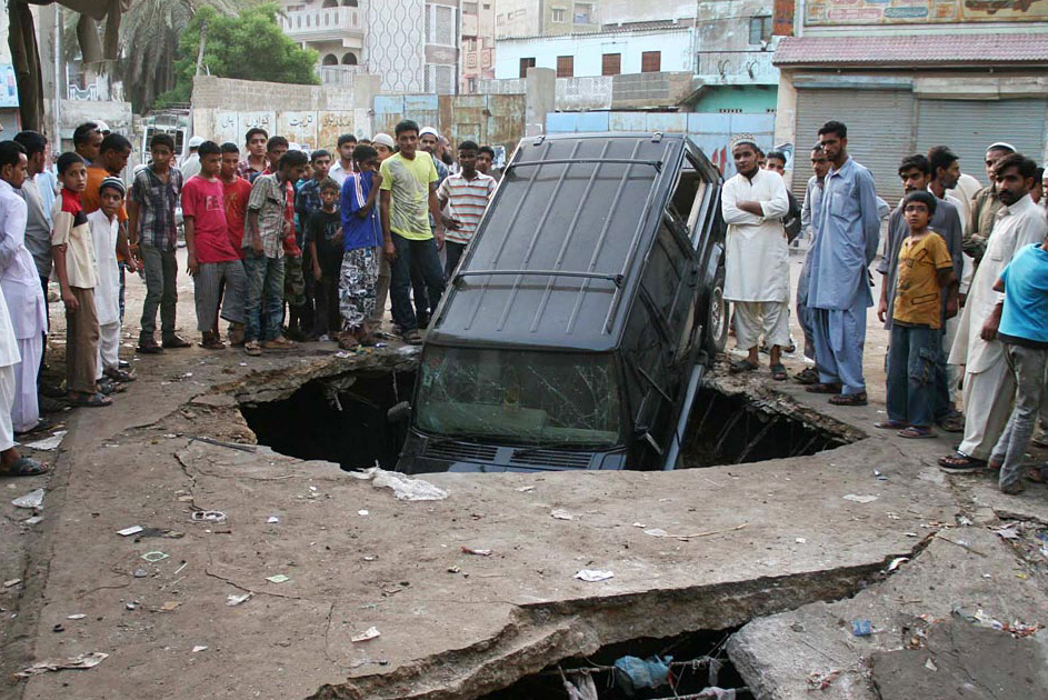 people standing near the car that was destroyed in the blast near football ground in lyari photo online