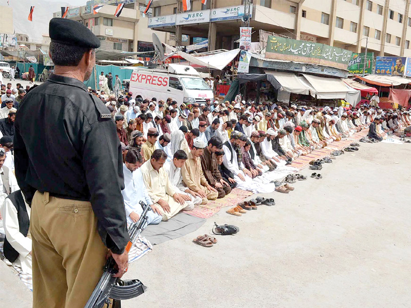 a policeman stands firmly at guard whilst muslims say their prayers photo file
