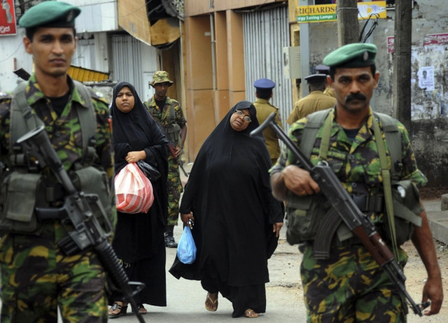 two muslim women walk behind patrolling special task force commandos outside a vandalized mosque in colombo photo reuters two muslim women walk behind patrolling special task force commandos outside a vandalized mosque in colombo photo reuters