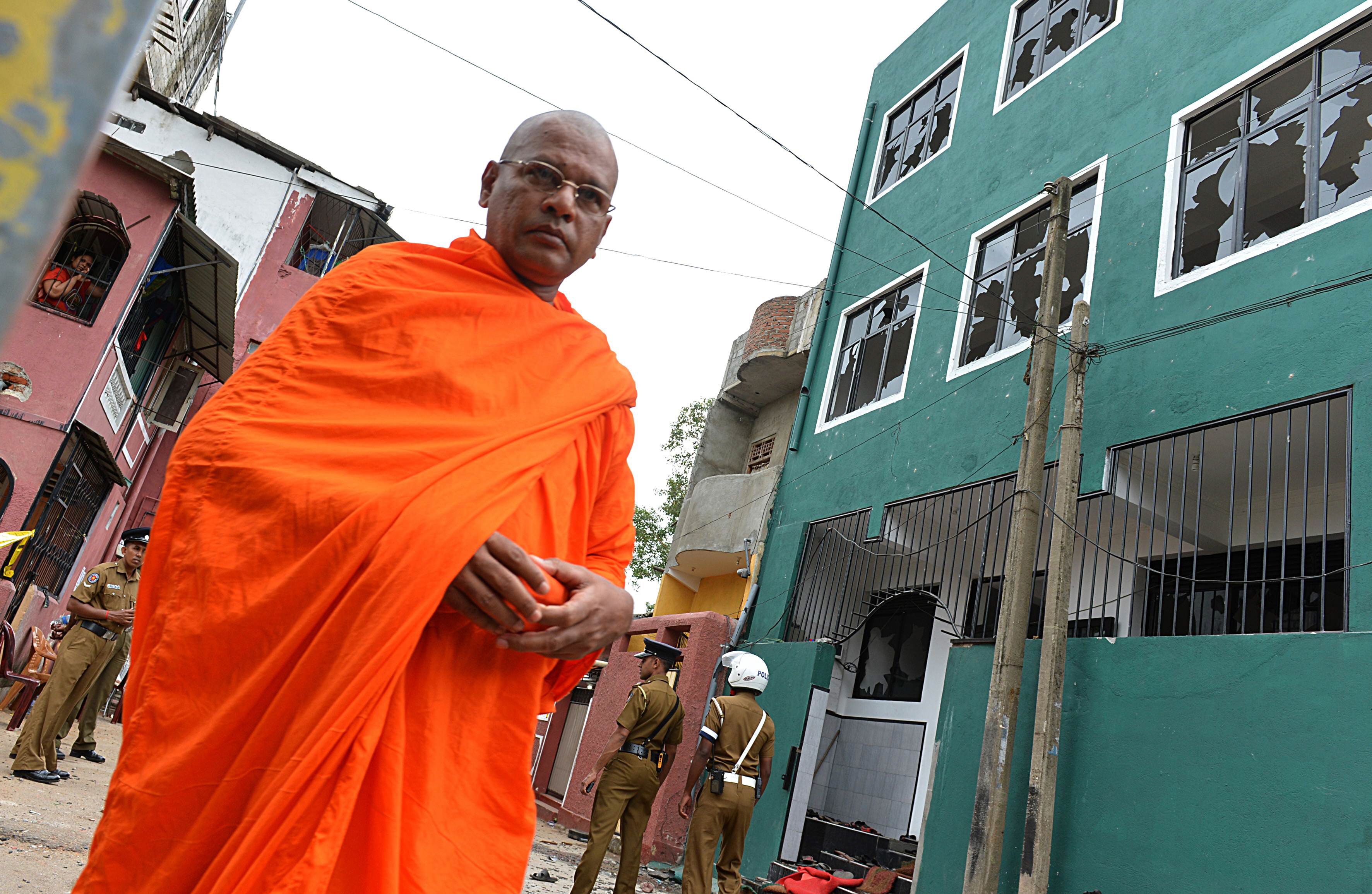 a sri lankan buddhist monk walks past a vandalized mosque in colombo on august 11 2013 sri lankan police deployed commandos and imposed a curfew on a colombo neighbourhood after a buddhist led mob attacked a mosque wounding four people and reviving simmering religious tensions officials said photo afp