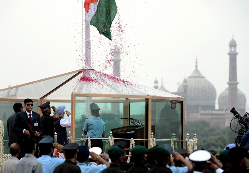 indian prime minister manmohan singh background 2nd r in blue turban salutes from a bulletproof glass enclosure on the ramparts of the red fort in new delhi on august 15 2013 on india 039 s 67th independence day photo afp