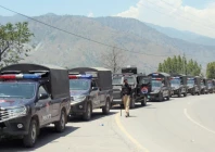a police officer stands guard beside a convoy of vehicles for police patrol in muzaffarabad photo reuters