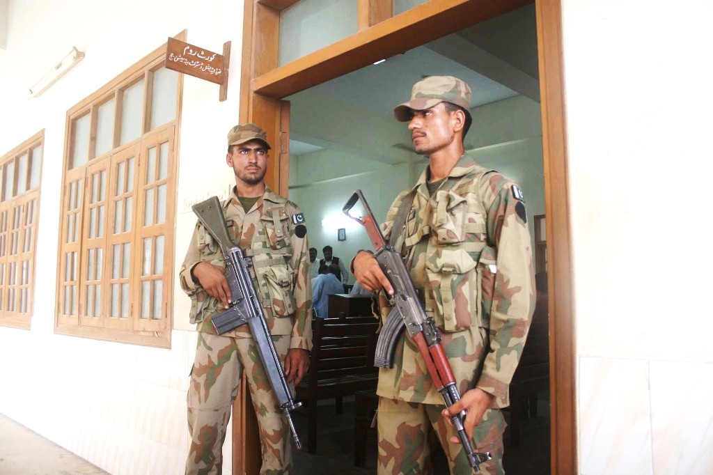 army officials standing at the gate of a polling station during by elections in ps 128 in karachi photo express file