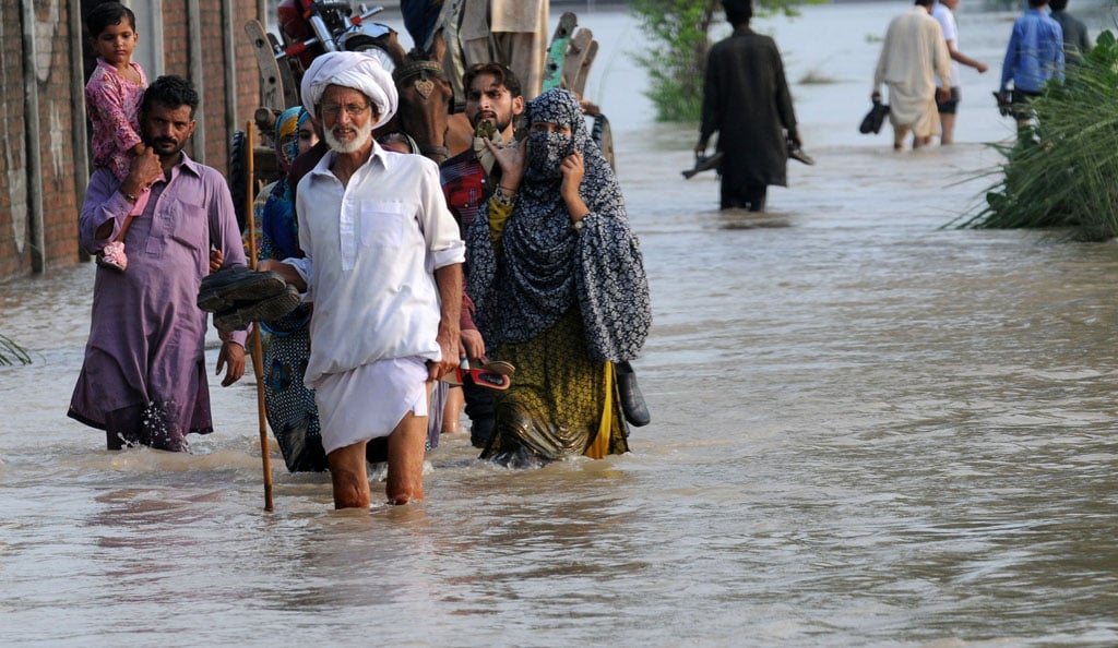 flood affected people walk through flood waters in muridke area near lahore on august 19 2013 photo afp