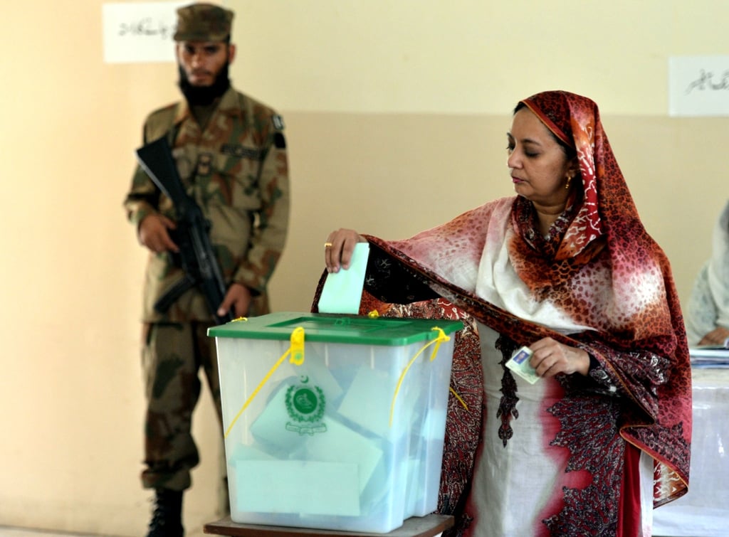 a pakistani soldier watches a woman as she casts her vote during the country 039 s by election in islamabad on august 22 2013 photo afp