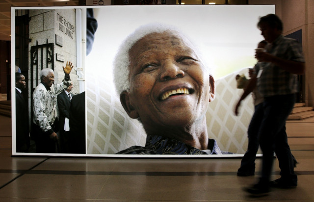 people walk on june 27 2013 past a giant picture of former south african president nelson mandela at the cape town civic center in the center of cape town photo afp people walk on june 27 2013 past a giant picture of former south african president nelson mandela at the cape town civic center in the center of cape town photo afp