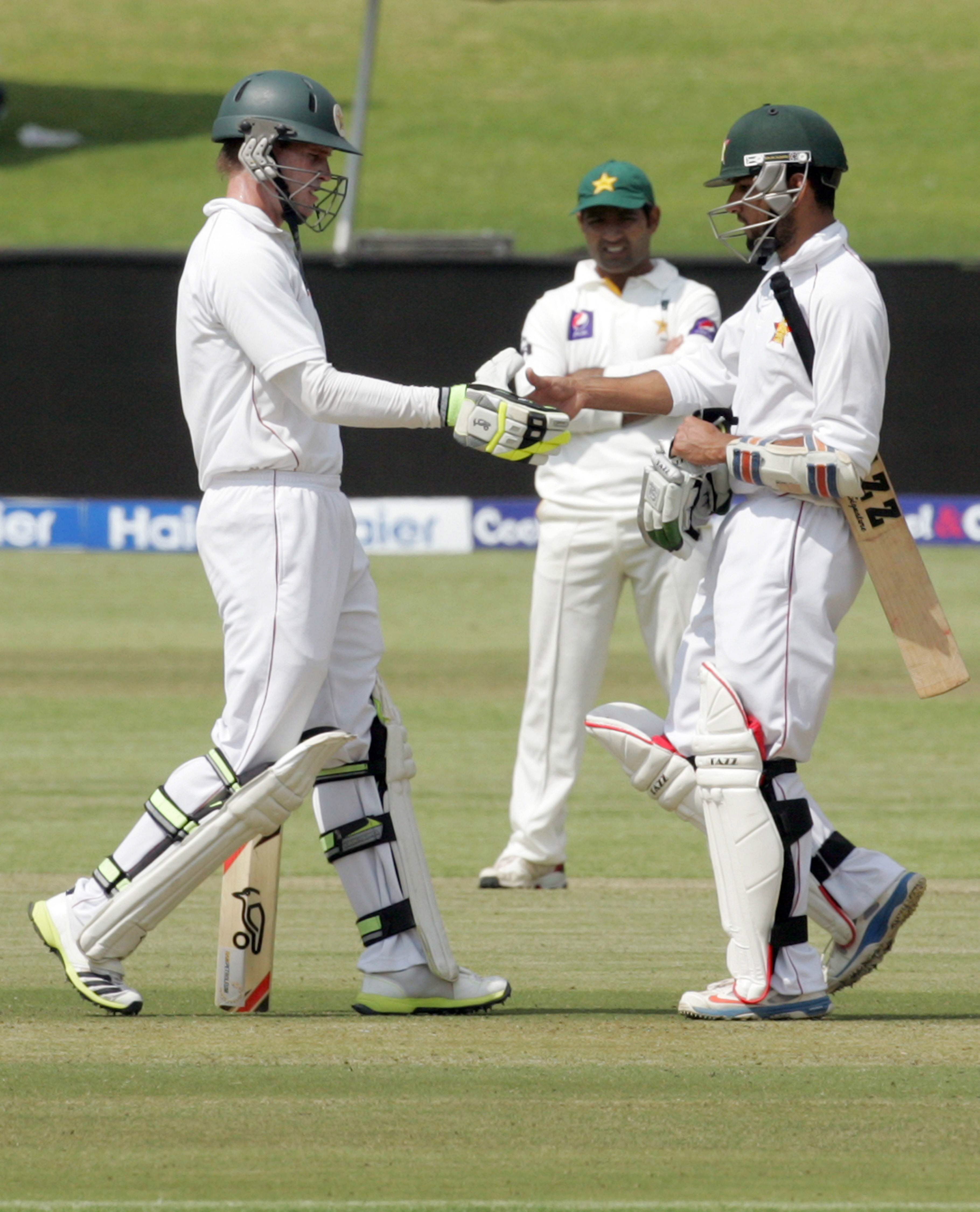 zimbabwe batsmen malcolm waller l and sikanda raza butt celebrate a 50 run partnership during the second day of the first test match on september 4 2013 photo afp