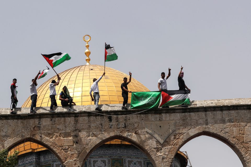 palestinians hold flags as they stand at the compound that houses al aqsa mosque known to muslims as noble sanctuary and to jews as temple mount in jerusalem s old city may 21 2021 photo reuters