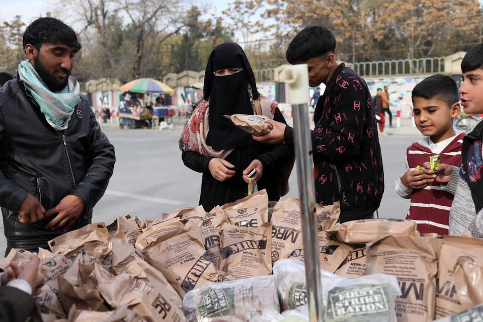 an afghan woman buys food left behind by the us military from a peddler in kabul afghanistan november 17 2021 reuters