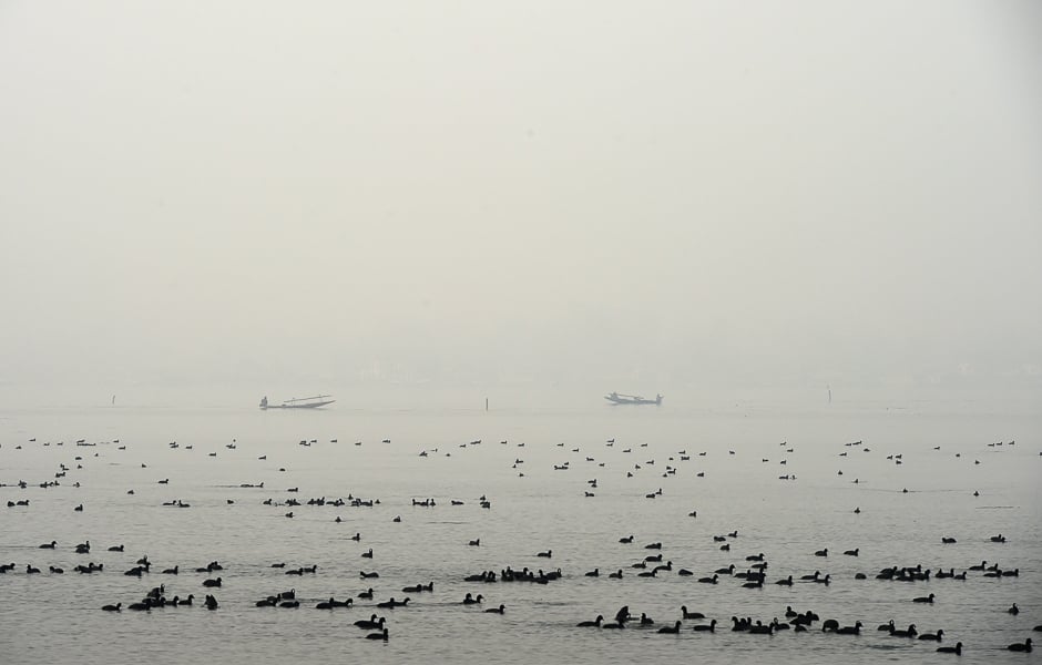 Kashmiri muslims ride boats in Dal lake during a foggy day in Srinagar. PHOTO: AFP