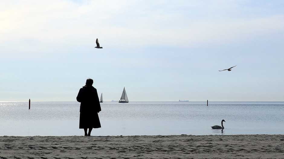 A woman, wrapped up against the cold wind, stands on the beach as she watches a swan and yachts in Gdynia, Poland. PHOTO: REUTERS