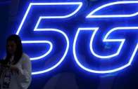 a woman looks at her mobile phone next to a 5g sign photo reuters