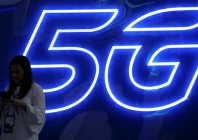 a woman looks at her mobile phone next to a 5g sign photo reuters