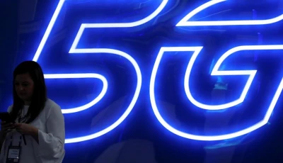 a woman looks at her mobile phone next to a 5g sign photo reuters