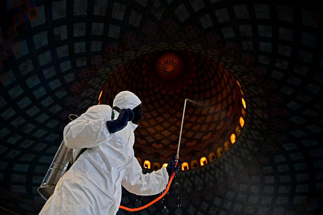 An officer of Local Disaster Mitigation Agency in protective suit sprays disinfectant at a mosque amid the spread of coronavirus in Surabaya, East Java province, Indonesia. PHOTO: Reuters