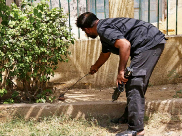 an official of the bomb disposal squad inspects a hand grenade found in kharadar on friday the misfired grenade was detonated by the bds experts as it could not be defused photo online an official of the bomb disposal squad inspects a hand grenade found in kharadar on friday the misfired grenade was detonated by the bds experts as it could not be defused photo online