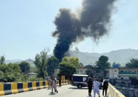 people and police gather near the crash site of a pakistan army aviation mi 17 helicopter near muzaffarabad as smoke billows from the wreckage photo reuters