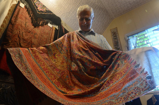 in this photograph taken on august 21 2013 mohammad sadiq wani a seller of the finest kashmir handicraft products displays a high quality hand embroidered pashmina shawl at his shop in srinagar weavers have produced exquisite shawls in kashmir for centuries but their craft risks dying out in the face of cheap foreign imports and a young generation uninterested in mastering the skill photo afp in this photograph taken on august 21 2013 mohammad sadiq wani a seller of the finest kashmir handicraft products displays a high quality hand embroidered pashmina shawl at his shop in srinagar weavers have produced exquisite shawls in kashmir for centuries but their craft risks dying out in the face of cheap foreign imports and a young generation uninterested in mastering the skill photo afp