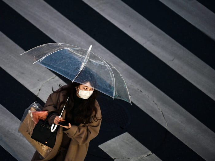 A woman crosses the street in Tokyo on January 28, 2021. CHARLY TRIBALLEAU/AFP