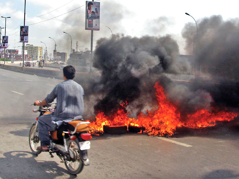 a motorcyclist passes by burning tyres during a city wide shutdown photo inp file