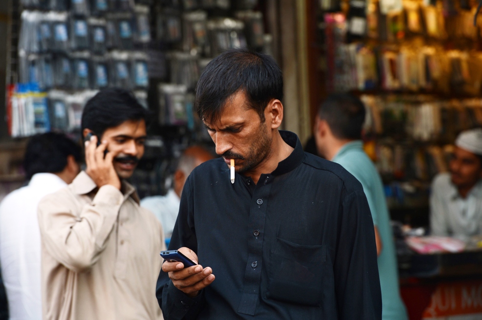 in this photograph taken on september 10 2013 a man checks messages on his mobile phone at a mobile market in rawalpindi photo afp