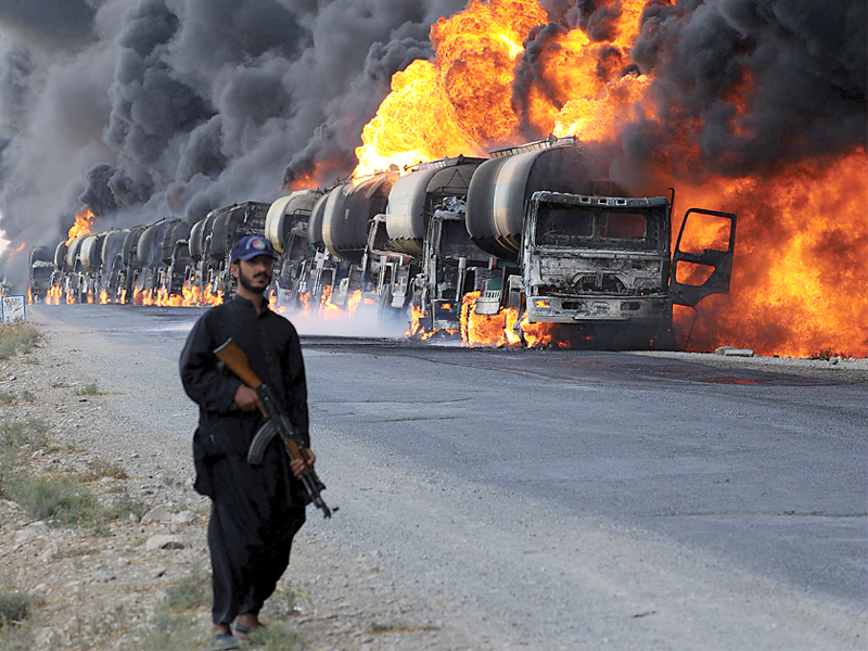 file photo of a policeman standing next to burning nato supply oil tankers photo afp