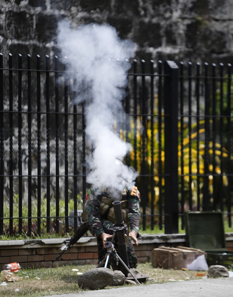 the head of a government soldier belonging to task force zamboanga is engulfed with smoke as he fires a 60mm mortar round towards the muslim rebels of moro national liberation front positions in zamboanga city in southern philippines september 16 2013 photo reuters