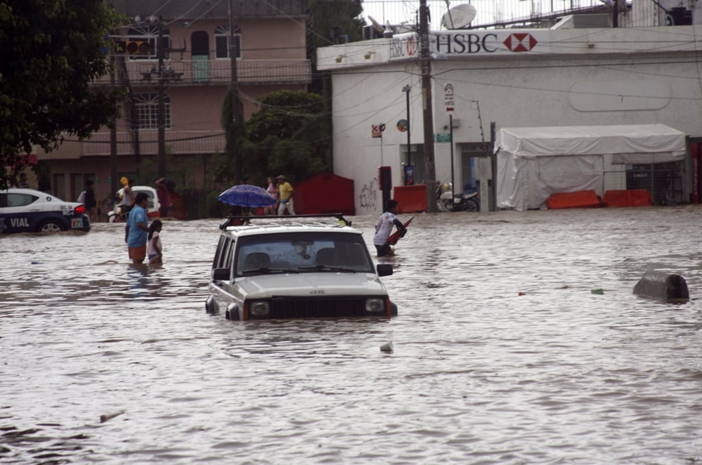 a car sits in a flooded street as people make their way through in acapulco september 15 2013 photo reuters