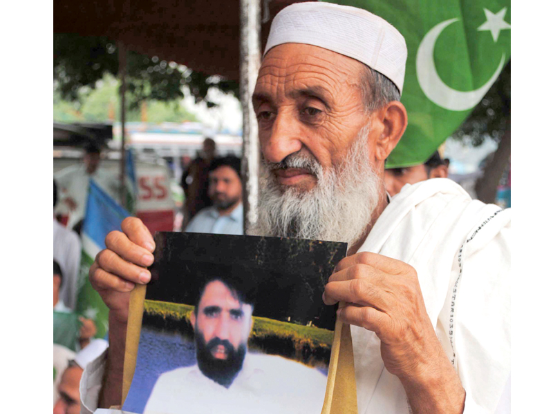 an elderly person holds a photo of his missing son at a protest photo muhammad iqbal express