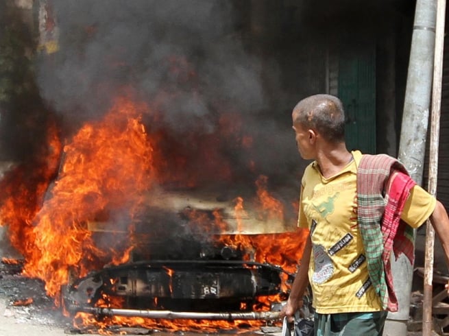 file photo of bangladeshi pedestrian walking past a burning vehicle after protests on september 17 photo afp