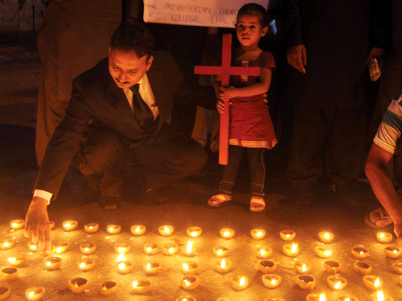 members of civil society light lamps during a peace vigil in lahore photo reuters